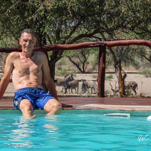 2024-05-06 - Wouter bij het zwembad met uitzicht op zebras en kudu<br/>Deception Valley Lodge - Central Kalahari Game Reserve - Botswana<br/>Canon PowerShot SX70 HS - 34.2 mm - f/5.6, 1/640 sec, ISO 100